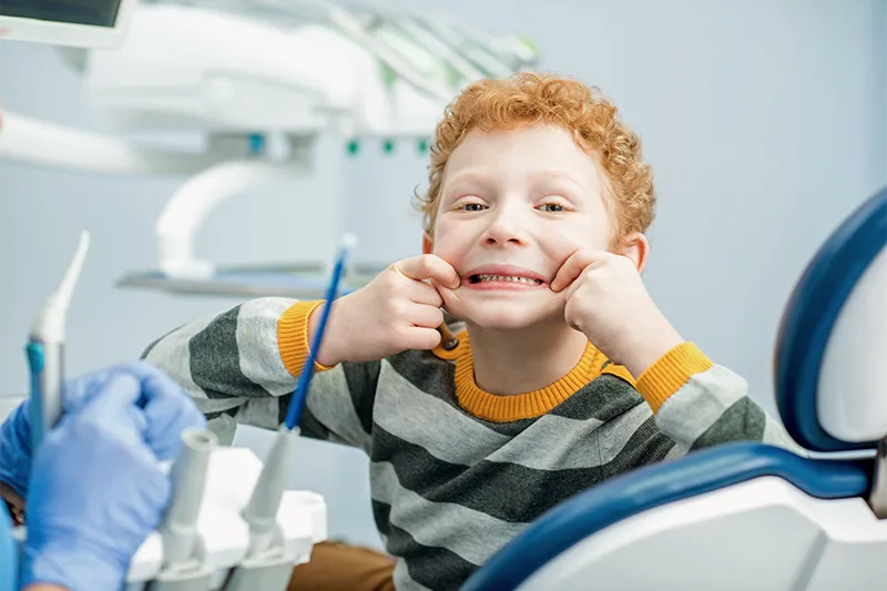 young boy smiling and holding cheeks