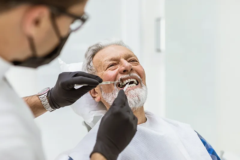 Dentist working on older man's teeth