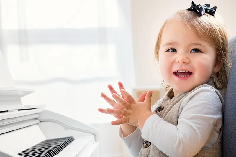 young girl smiling next to piano