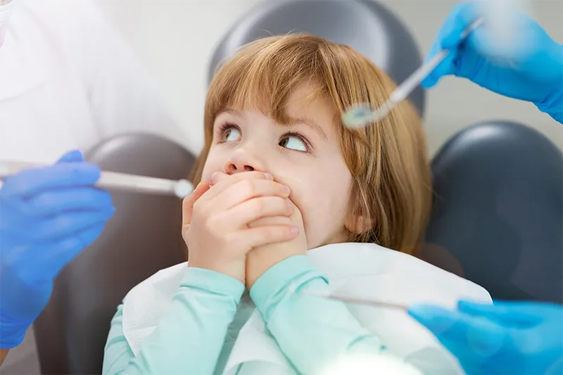 young girl covering mouth at dentist